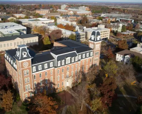 Historic brick university building surrounded by autumn trees on campus
