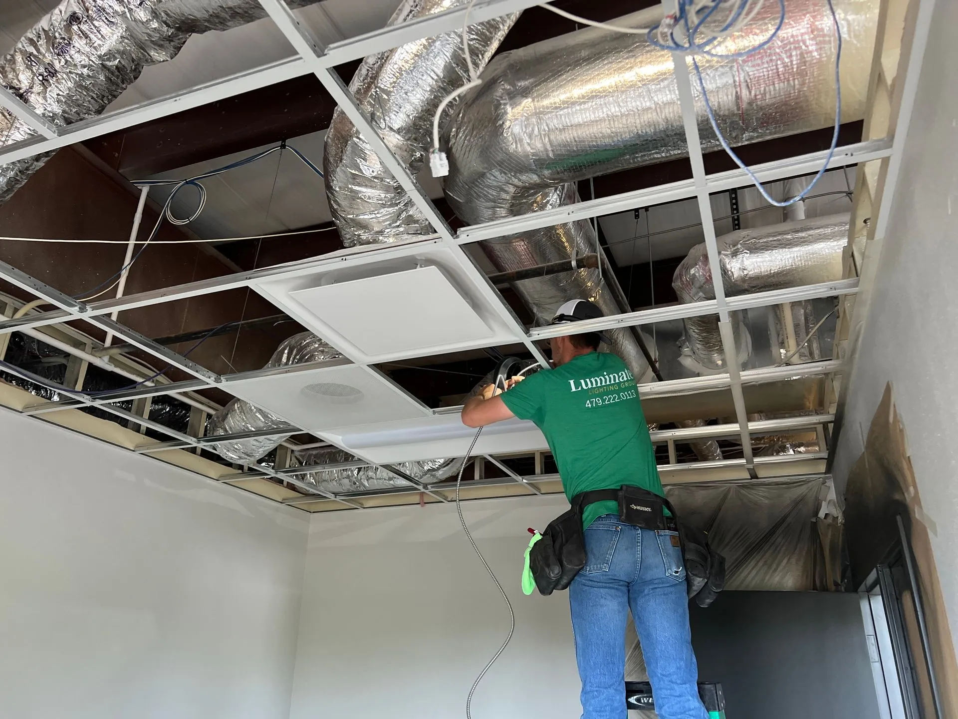 Technician installing ceiling tiles and HVAC ducts in commercial space