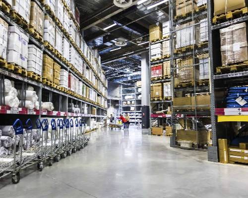 Large warehouse interior with stacked shelves, pallets, and metal shopping carts