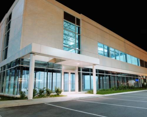 Modern two-story office building with glass facade and parking lot at dusk