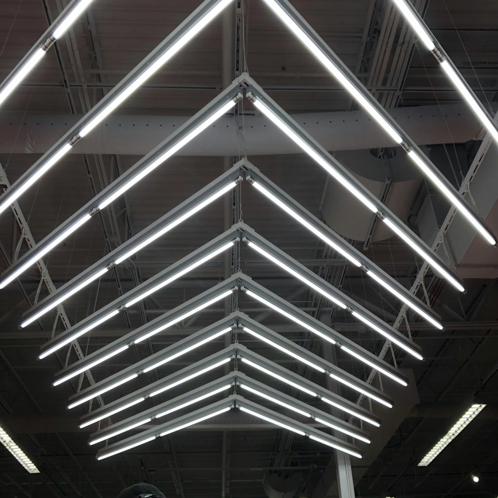 Geometric pattern of bright white fluorescent lights on industrial ceiling