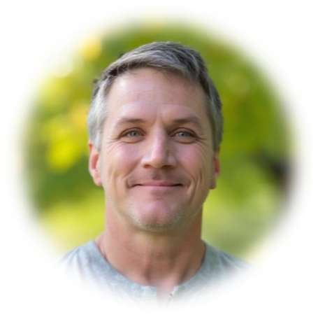 Smiling middle-aged man in gray shirt with blurred green background