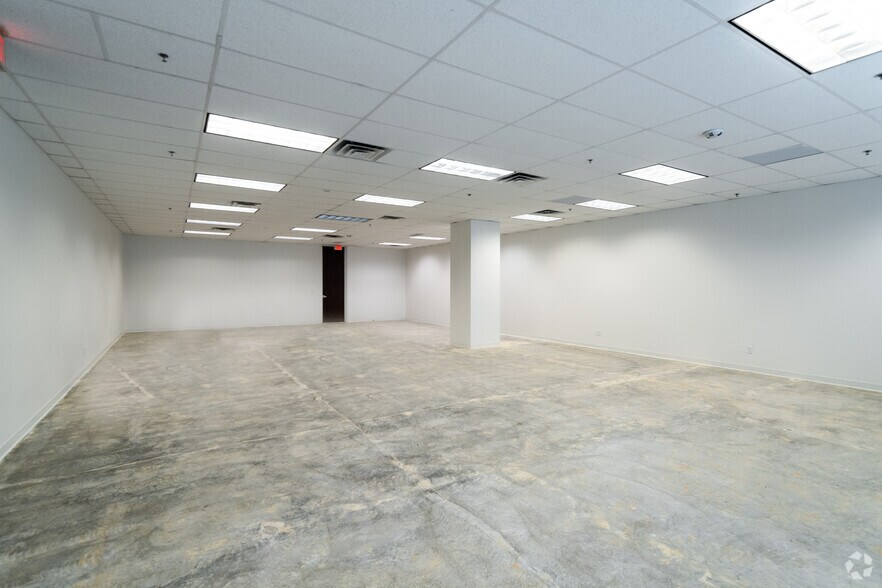 Empty white office space with concrete floor and fluorescent ceiling lights