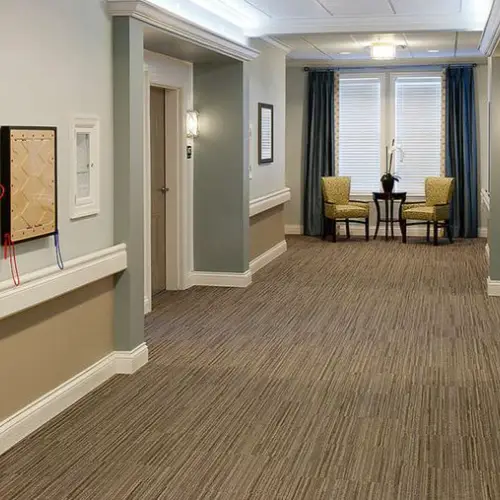 Hallway with wood-like flooring, yellow chairs, and large windows with curtains