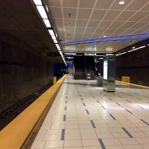 Empty subway station platform with escalators and tiled floor
