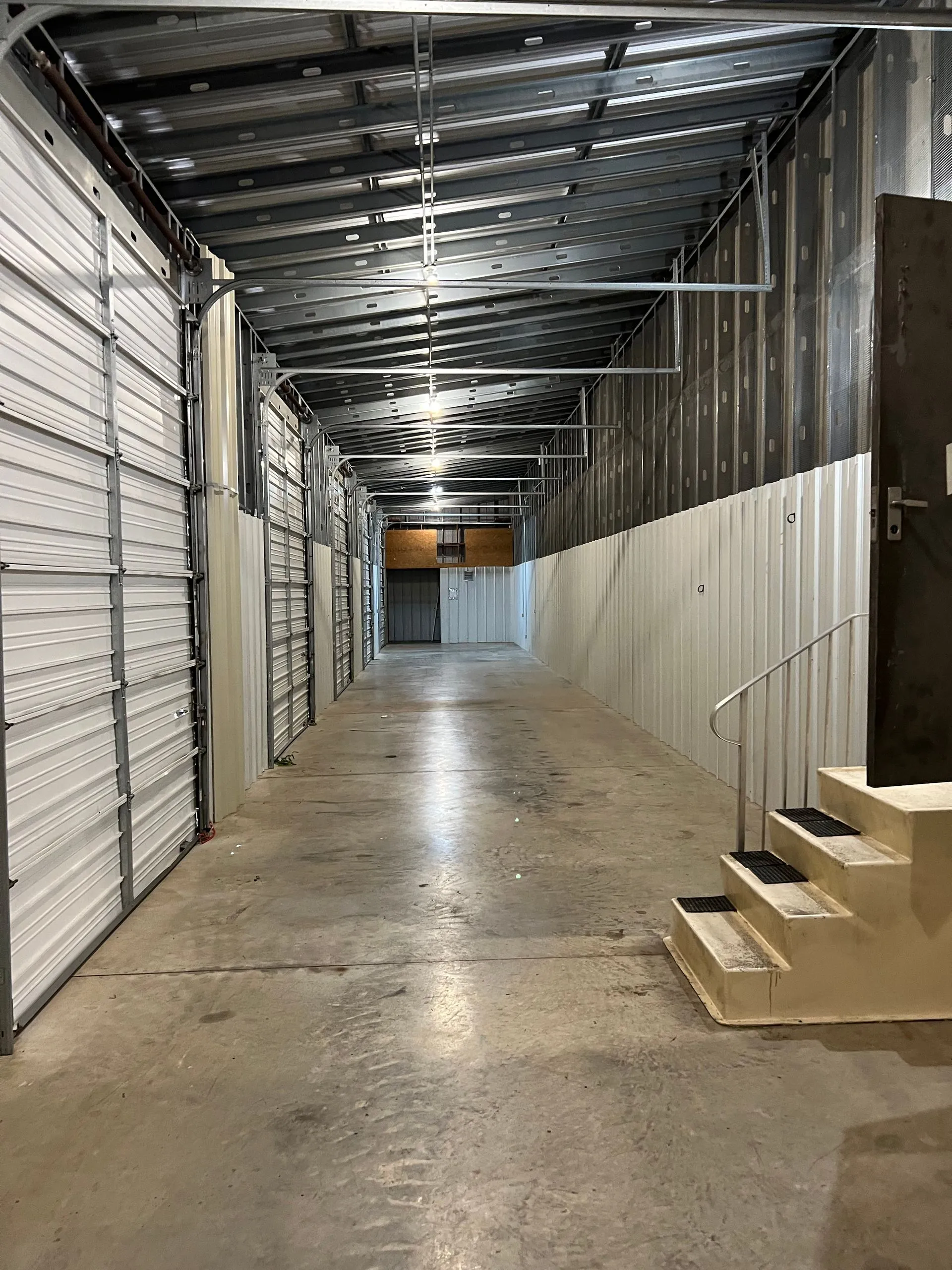 Interior of a storage facility with metal doors and concrete walkway