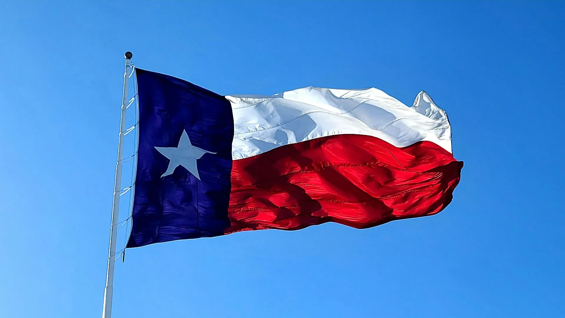 Texas state flag waving against bright blue sky