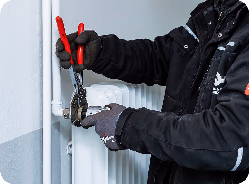 WTH-Handwerker schraubt an einer Heizung