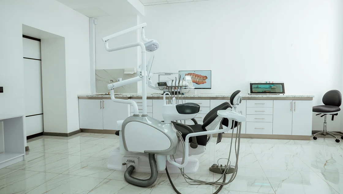A dentist chair in a room with a computer.