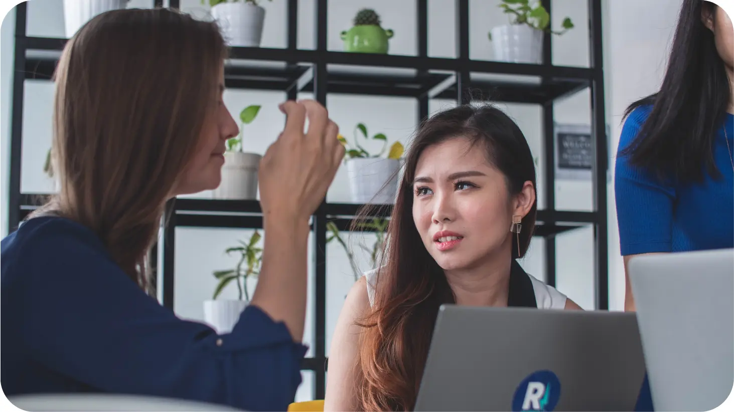 Coworkers working and talking with their laptop open