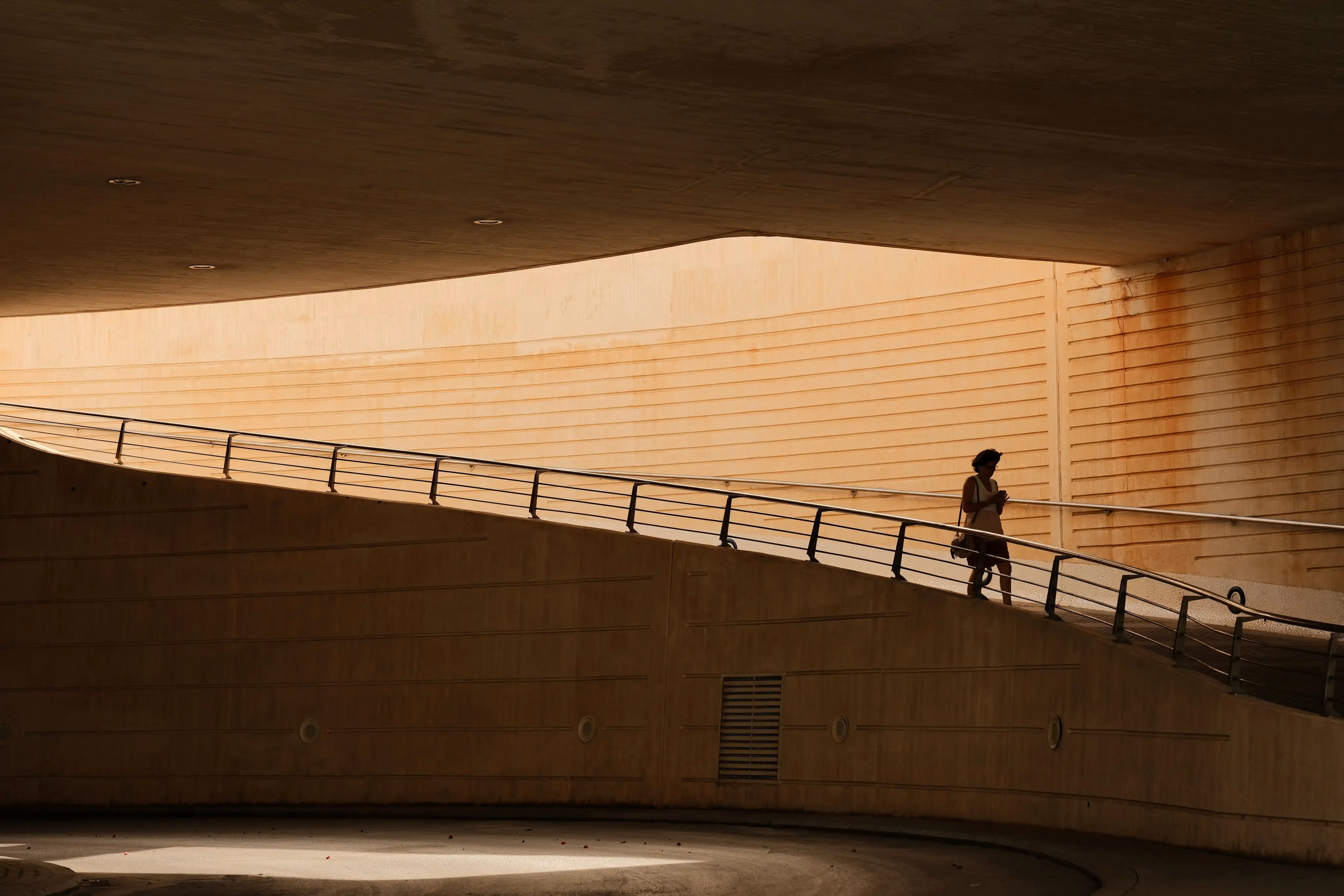 Person walking down a ramp in a concrete building