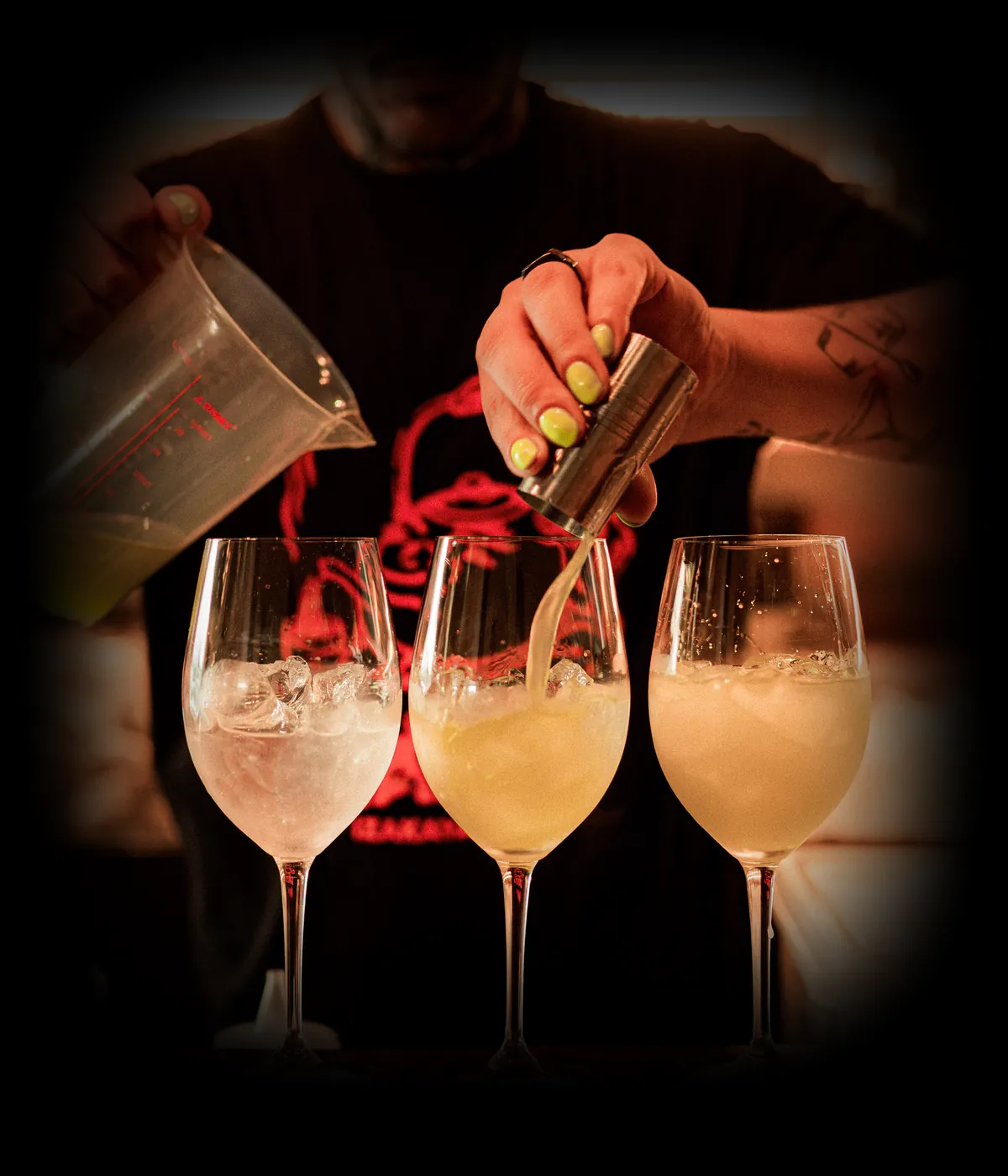 Bartender do Santo Izakaya a servir três cocktails ao balcão