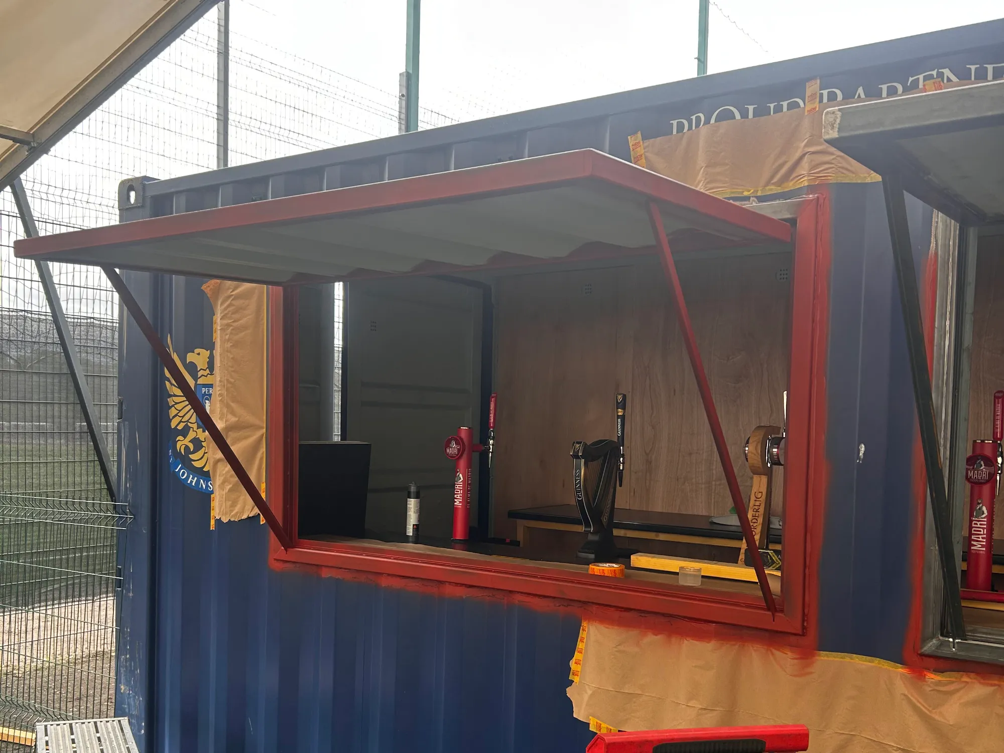 Converting a shipping container into a functioning drinks bar at the St.Johnstone Football Club fanzone by installing two hinged serving hatches.