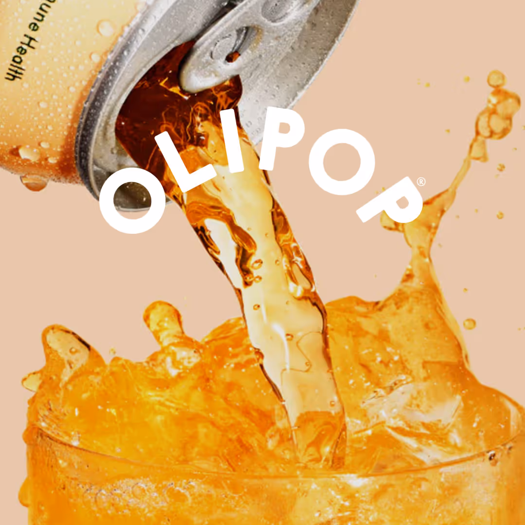 Close-up of an open can pouring an amber-colored fizzy drink into a glass with splashes, with the word OLIPOP overlayed.