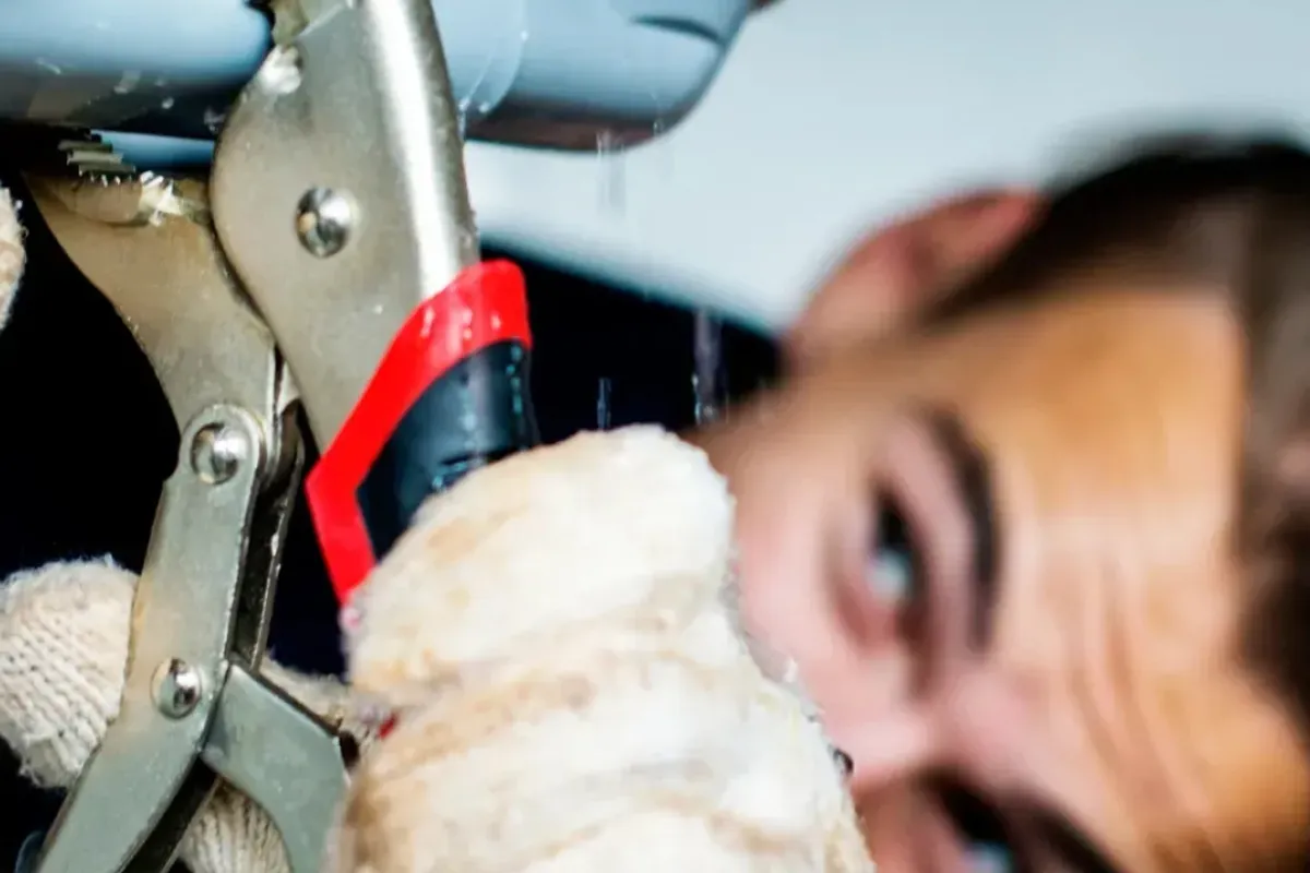 A person fixing the leaking pipe.