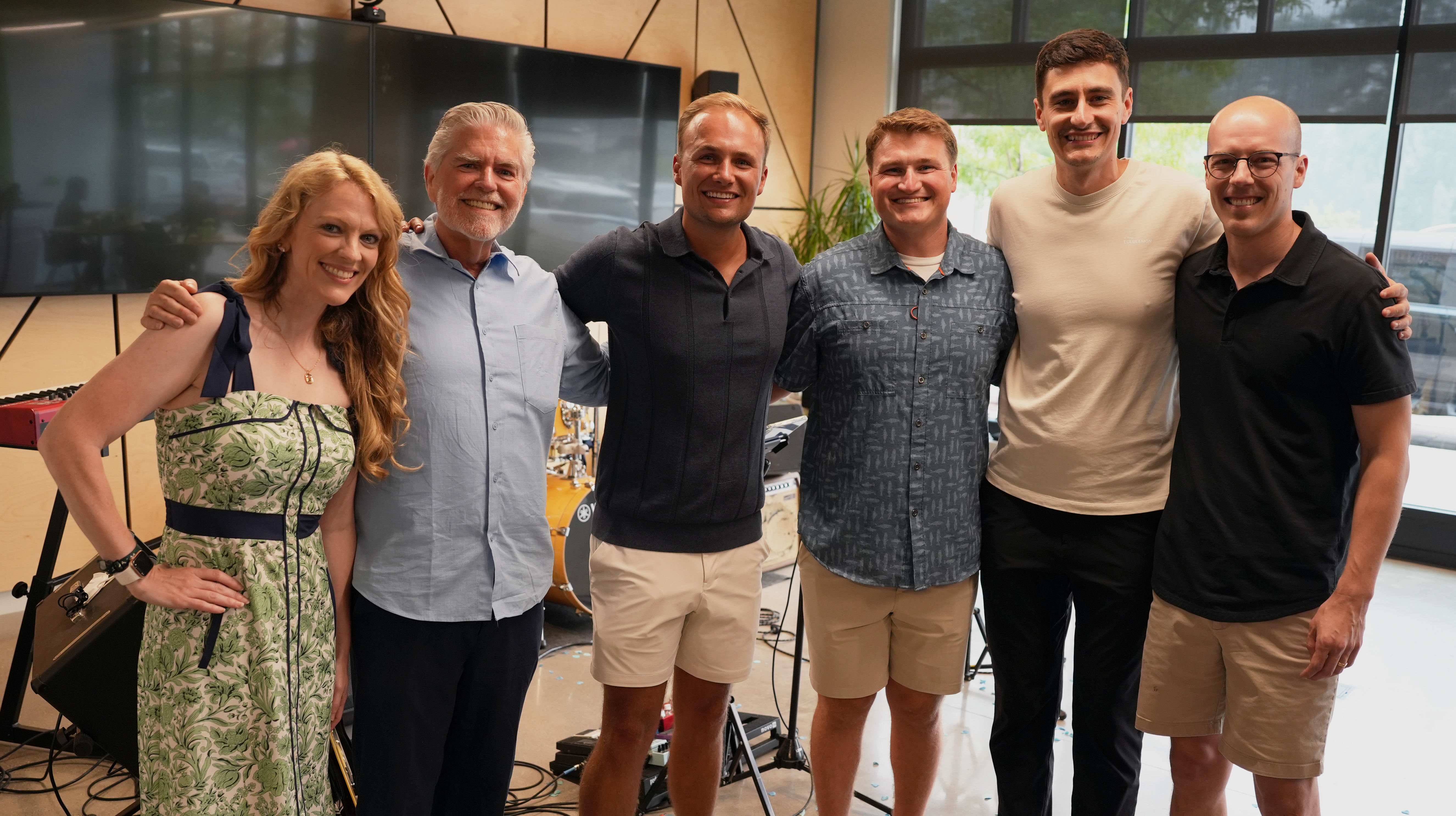 Company leadership team posing together in a studio space with music gear behind them.