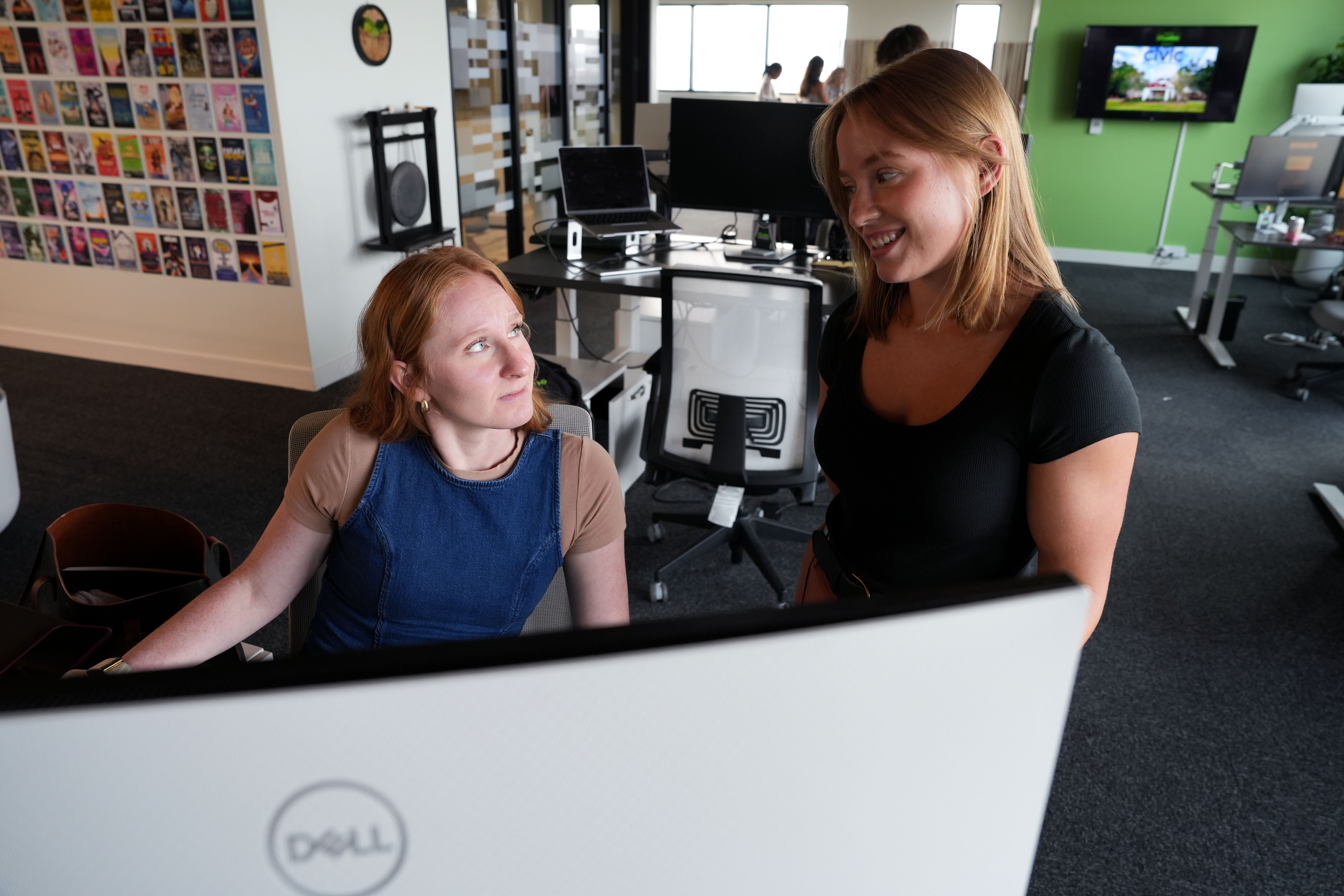 O'Malley Ferguson and Hannah Schmidt discussing work together at a computer desk during the 10-year celebration at the Ada office.