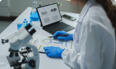 A scientist in a lab coat looks at medical data on a monitor, representing advanced research.