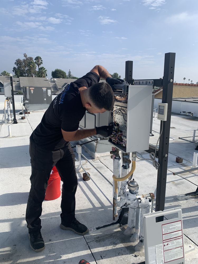 Technician working on an HVAC unit on a commercial rooftop.