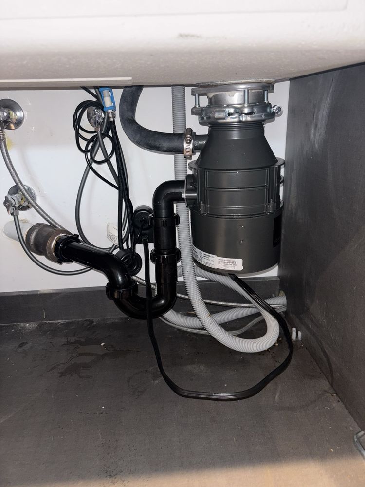 Garbage disposal and plumbing pipes installed under a kitchen sink.