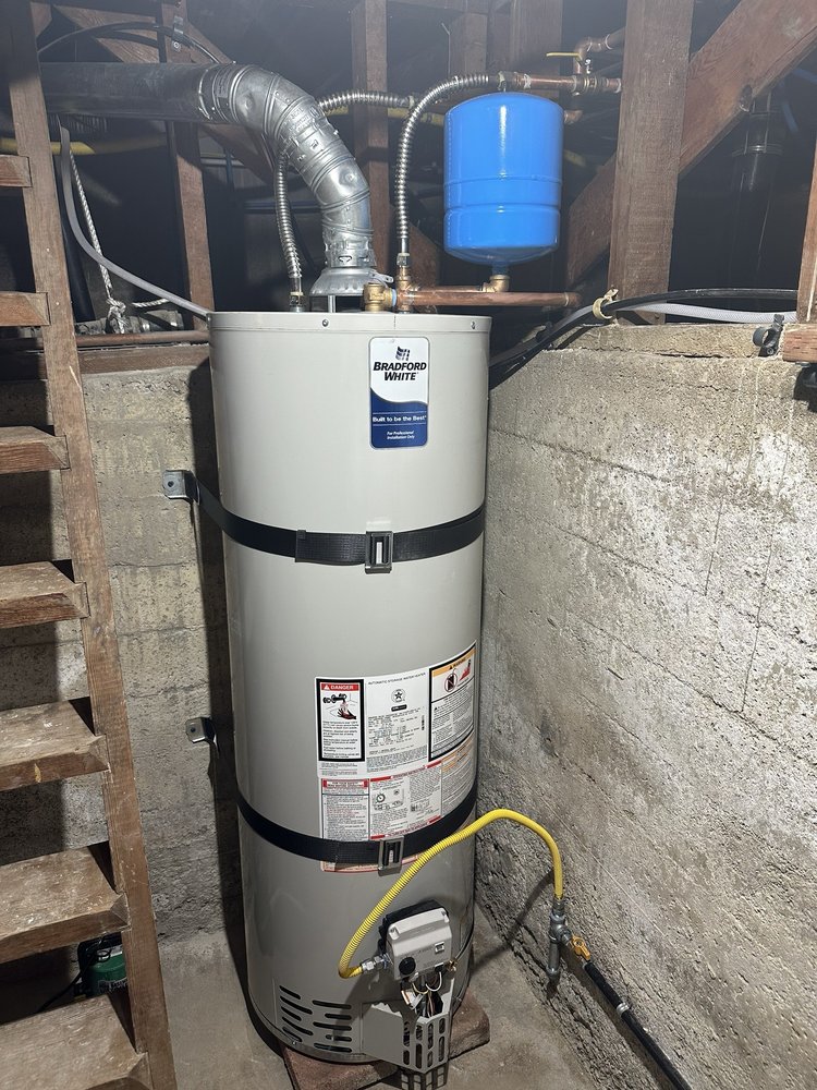 Water heater installed in a basement with pipes and expansion tank.