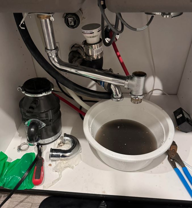 Drain installation in Pasadena CA displaying new plumbing fixtures with garbage disposal and drain components under sink