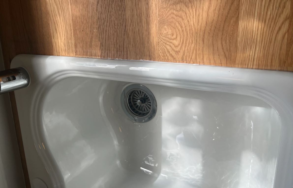 Drain repair in Pasadena CA showing close-up of white ceramic kitchen or bathroom sink with visible drain opening