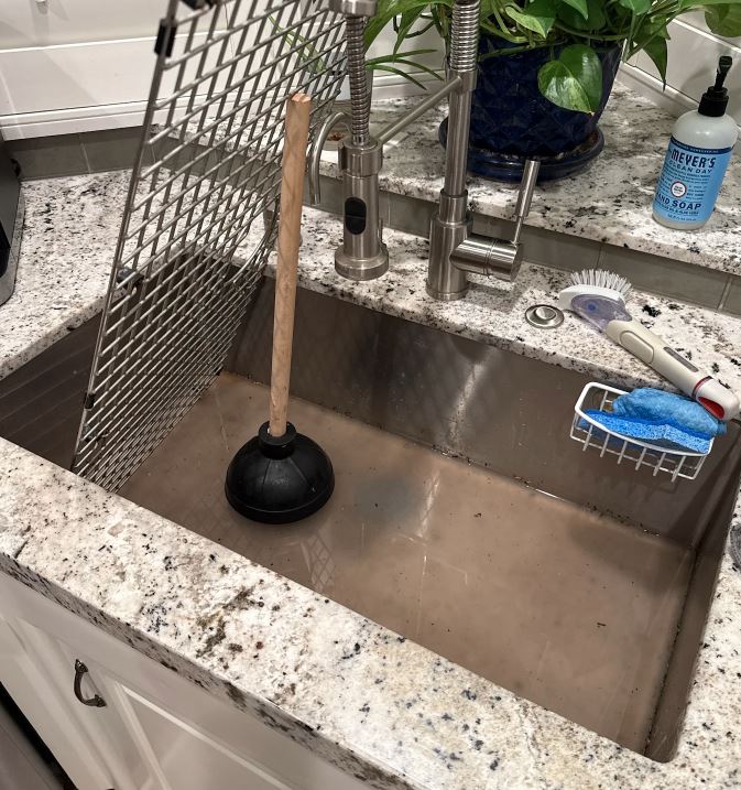Professional drain cleaning service in Pasadena CA showing plunger removing blockage from kitchen sink