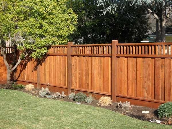 Stained cedar privacy fence with decorative Alta top design featuring vertical cutouts