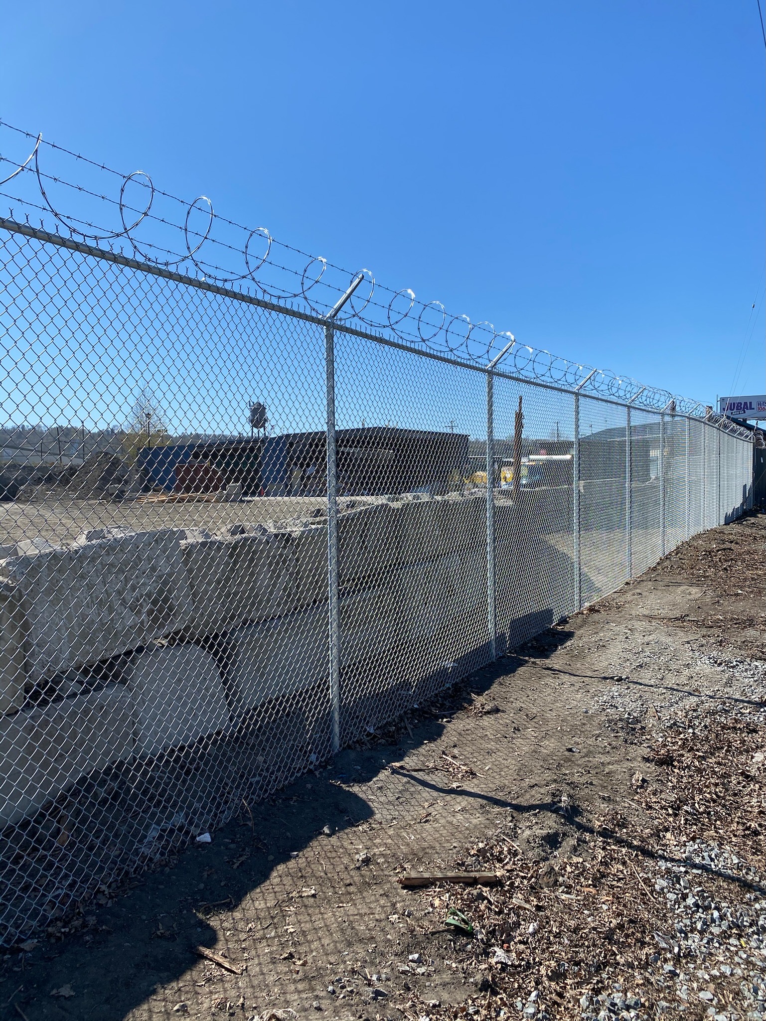 Chain link security fence with barbed wire top enclosing a commercial or industrial lot