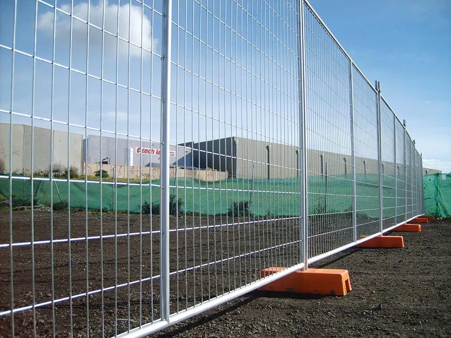 Temporary fencing with welded wire mesh panels on orange feet along a construction site