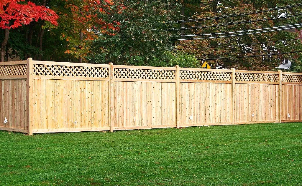 Natural wood privacy fence featuring a top diagonal lattice accent section along a green lawn.