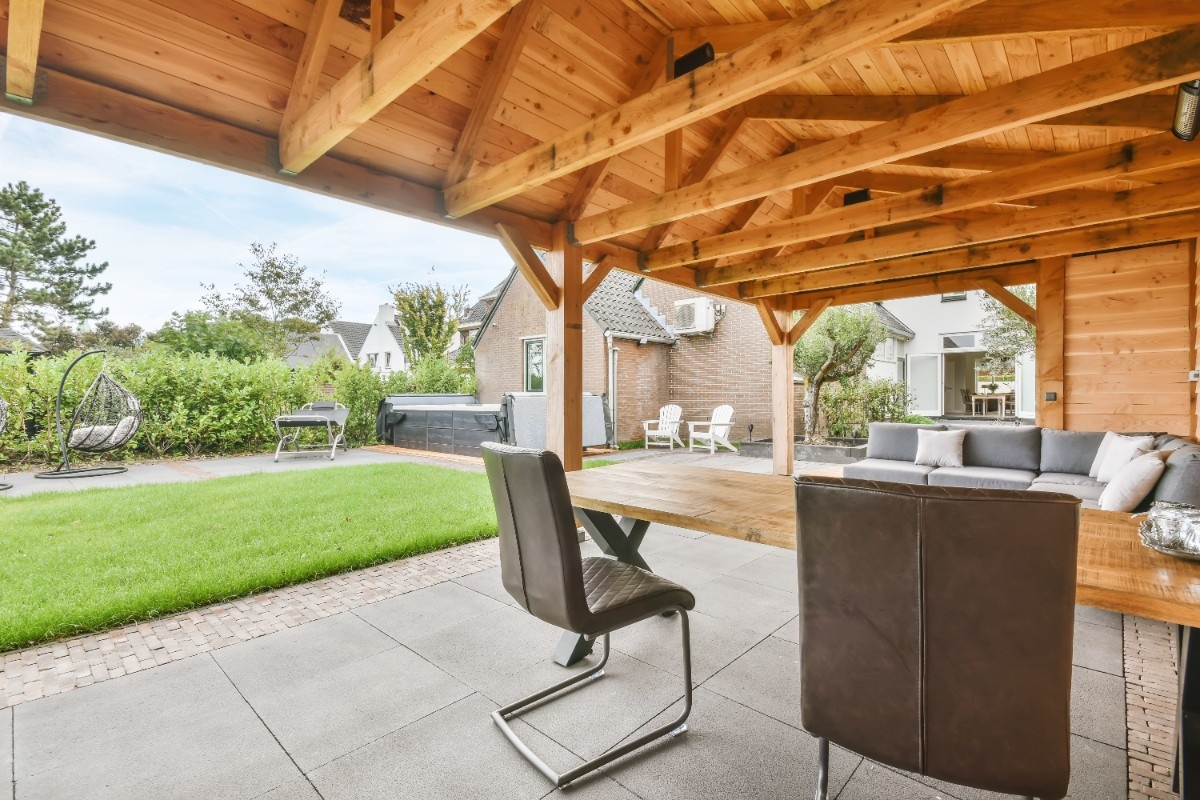 Outdoor sofa and dining table under a wood-framed patio cover
