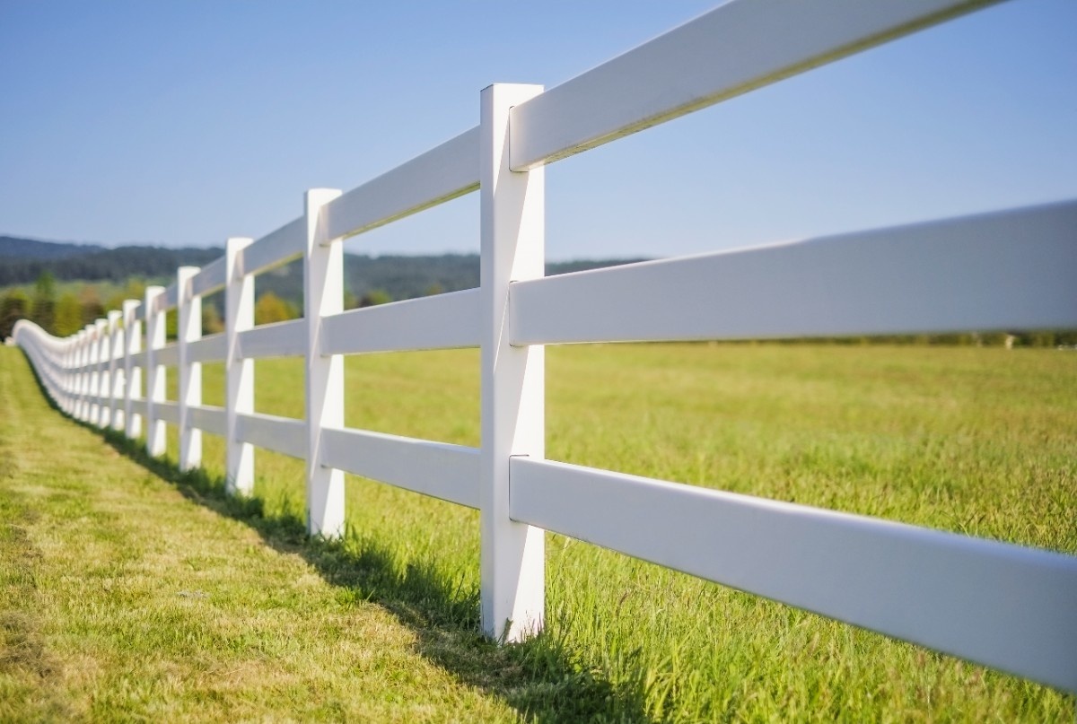 White vinyl pasture rail fence lining an open property near Seattle