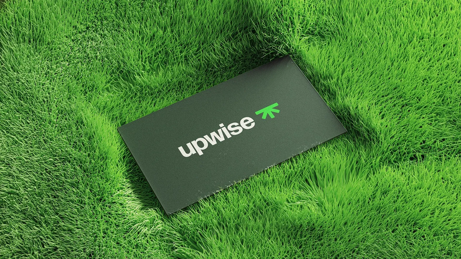 Visitekaartje ontwerp met het groene Upwise logo, gepresenteerd op gras, branding en grafisch ontwerp door East Creatives."