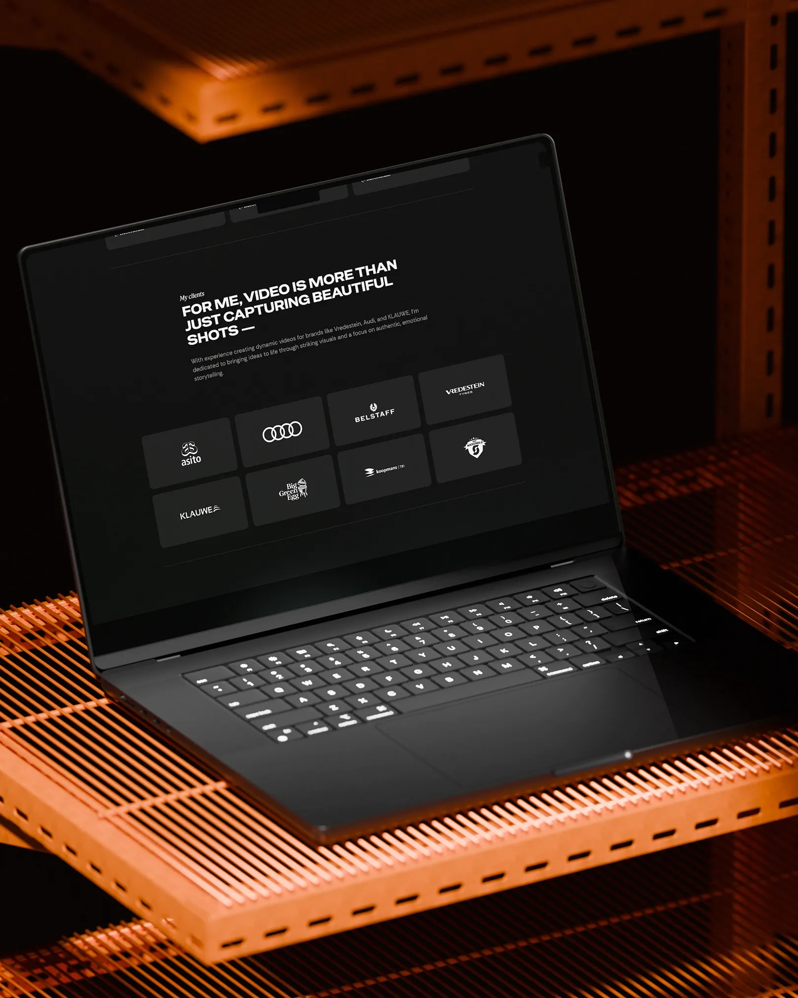 Laptop mockup met klantenoverzicht van videoprojecten door East Creatives, merken als Audi, Belstaff, Vredestein en Asito in strak zwart design.