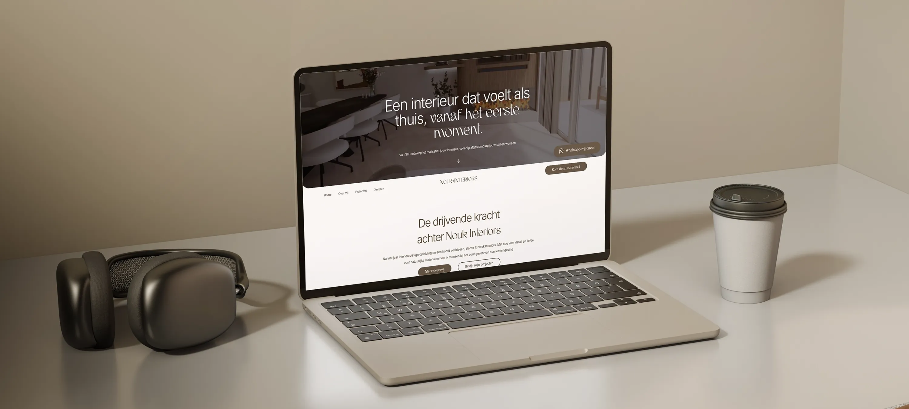 Laptop op bureau toont de homepage van Nouk Interiors met slogan ‘Een interieur dat voelt als thuis’, naast een koptelefoon en koffiebeker – modern webdesign voor interieurontwerpstudio.