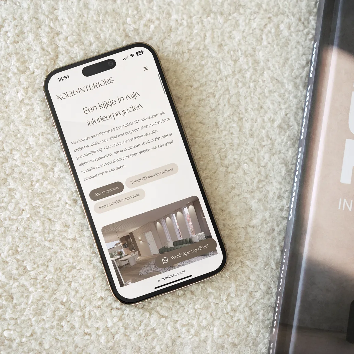Smartphone op licht tapijt toont de mobiele website van Nouk Interiors met interieurprojecten en 3D-ontwerpen – modern webdesign voor interieurontwerper in Enschede.