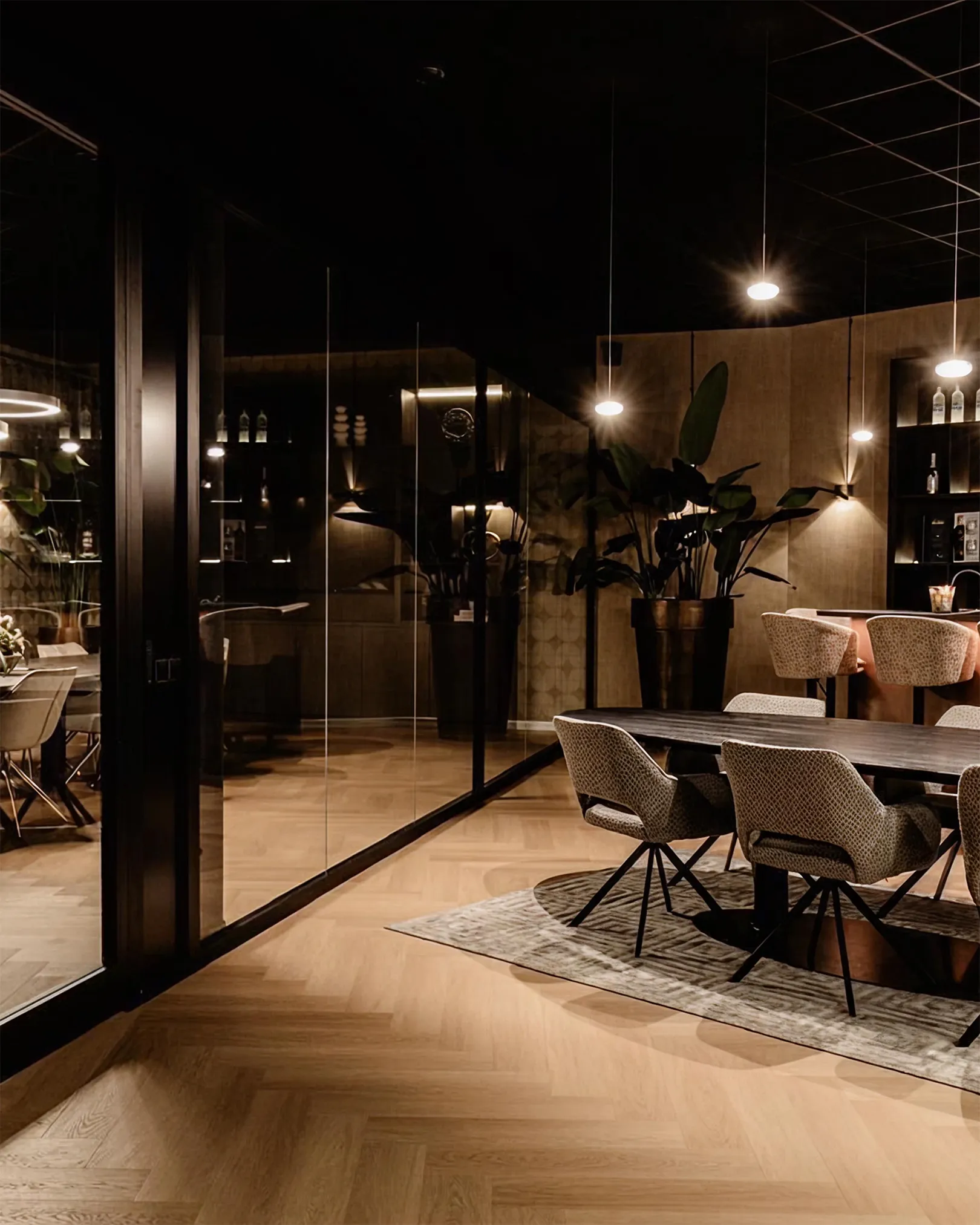 Sfeervol verlichte lounge- en vergaderruimte bij VDM Cars in de avond, met hanglampen en wandverlichting door Halo Lighting.