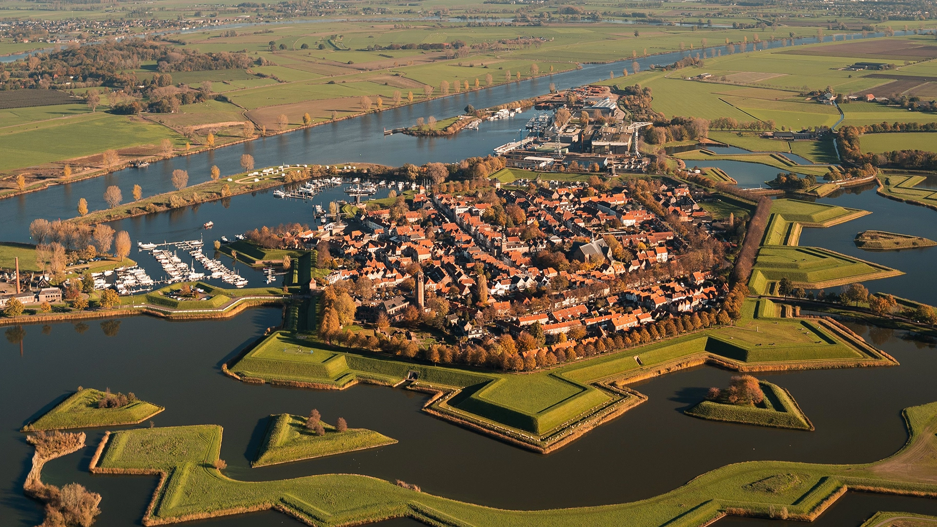 Luchtfoto van een vestingstad met stervormige aarden wallen, water en rode daken, als sfeerbeeld bij logo-ontwerp in Overijssel