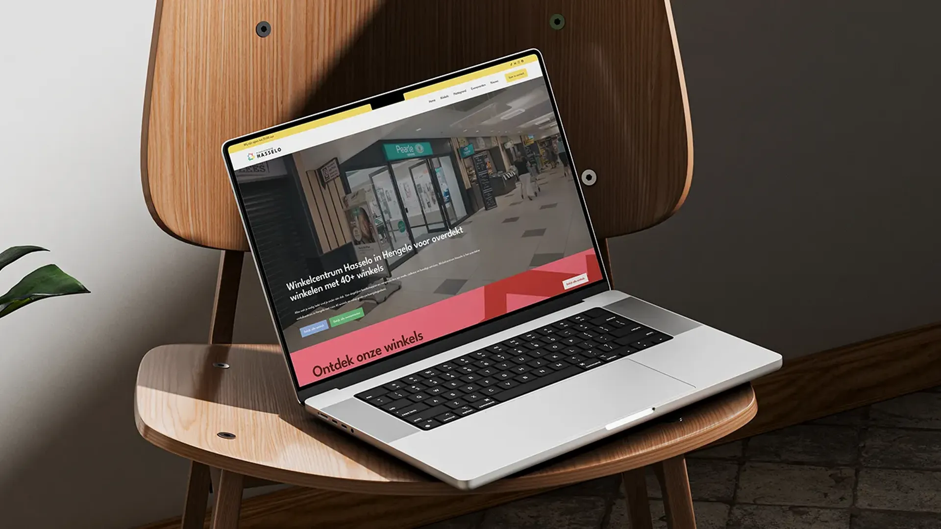Laptop op een houten stoel met de website van Winkelcentrum Hasselo geopend, een voorbeeld van branding en website die naadloos op elkaar aansluiten