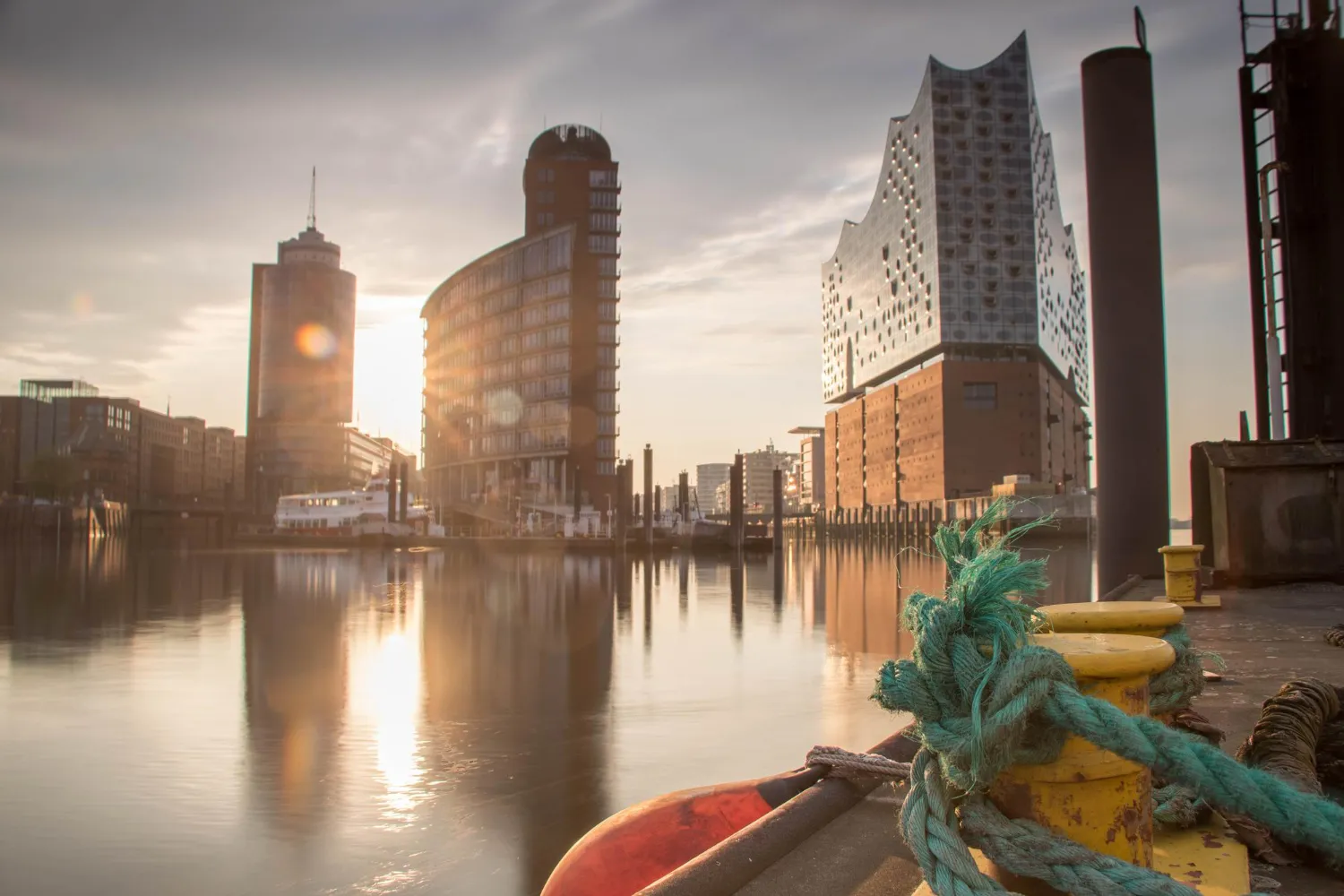 Sonnenuntergang am Hamburger Hafen mit moderner Architektur und Spiegelungen im Wasser.