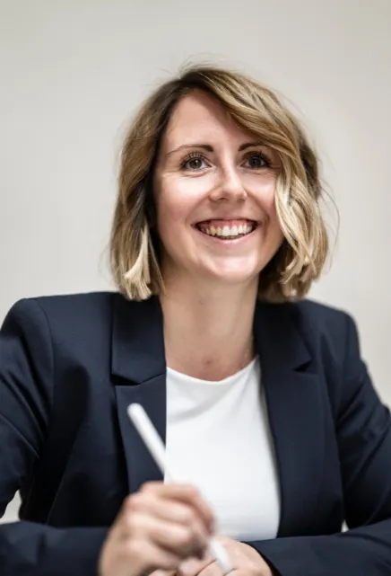 Lächelnde Rechtsanwältin in dunkelblauem Blazer während eines Gesprächs.