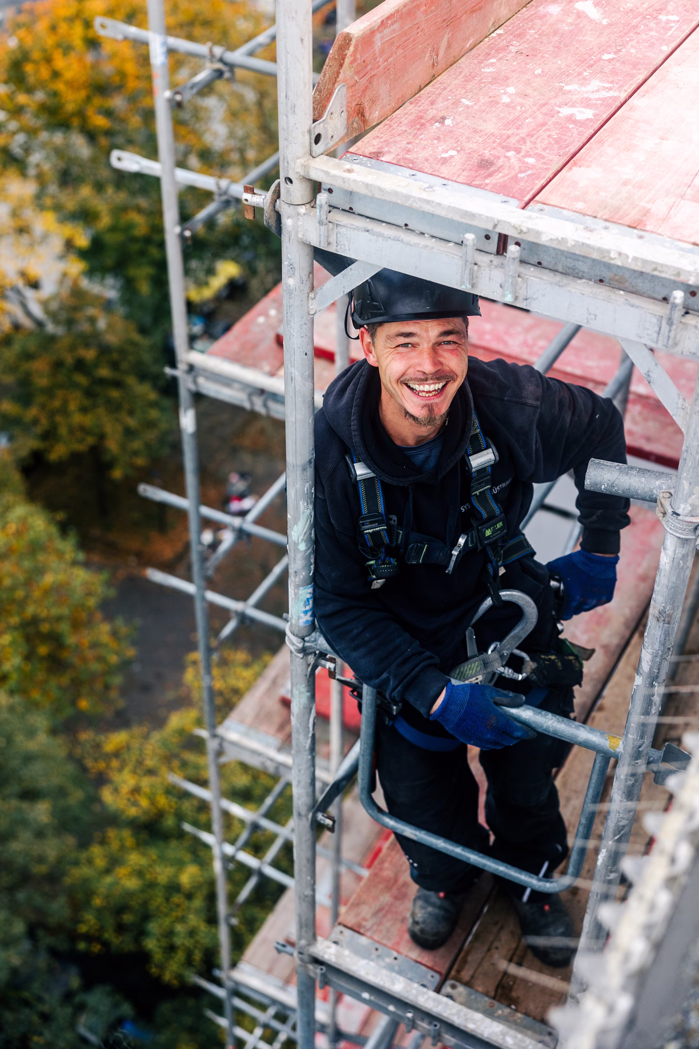 Social Media Werbeagentur: Lächelnder Arbeiter auf Baugerüst in Herbstlandschaft