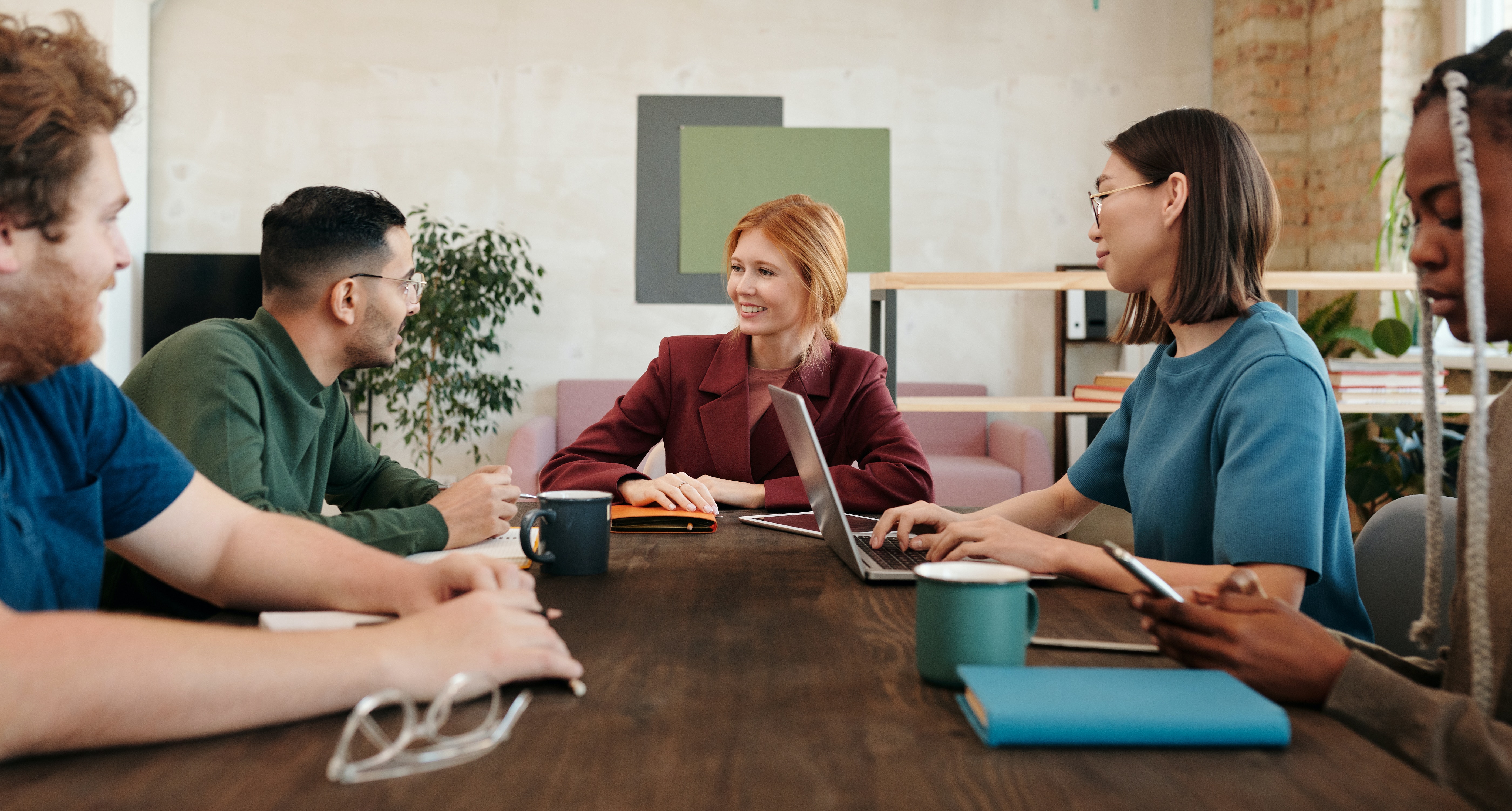 A group of coworkers having a relaxed discussion while seated in a casual office lounge.