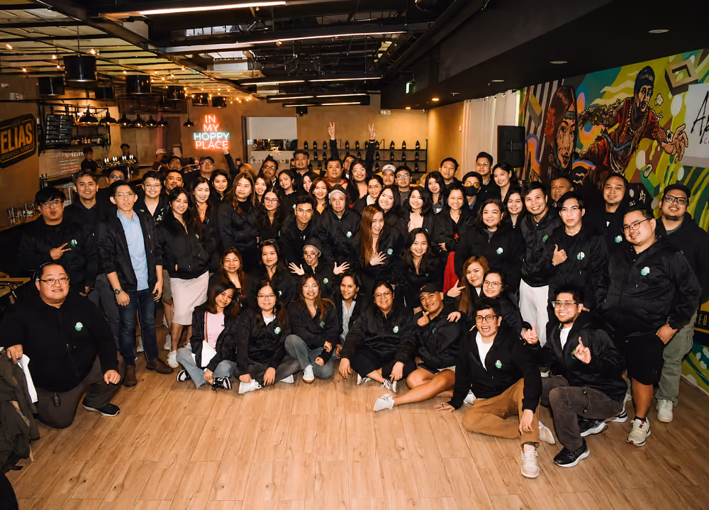 Large team photo of GrowthAssistant employees smiling together at a bar event.