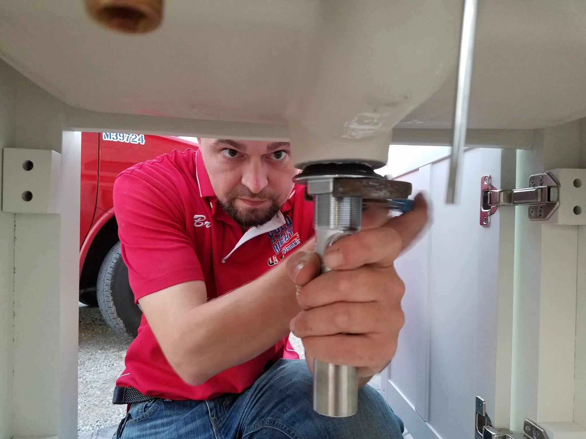 Plumber fixing sink drain under cabinet.