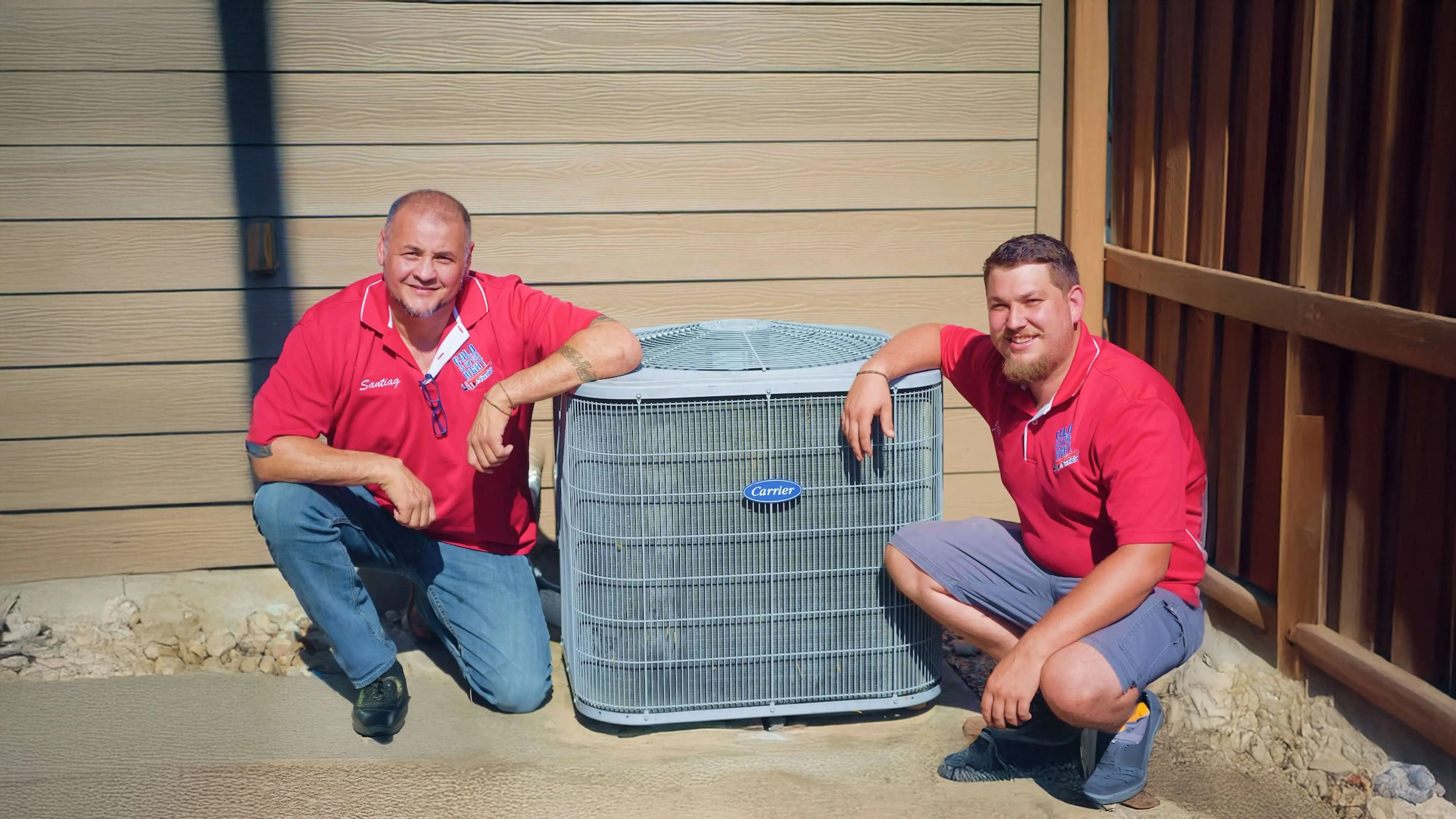 Two HVAC team members smiling, posing with outdoor air conditioner unit.