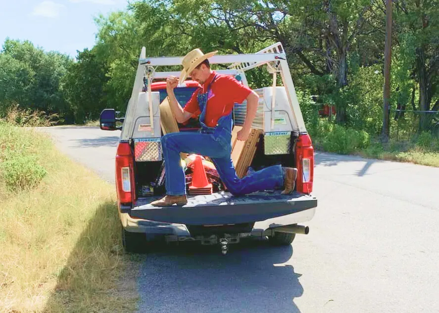 Plumber posing heroically in truck bed.