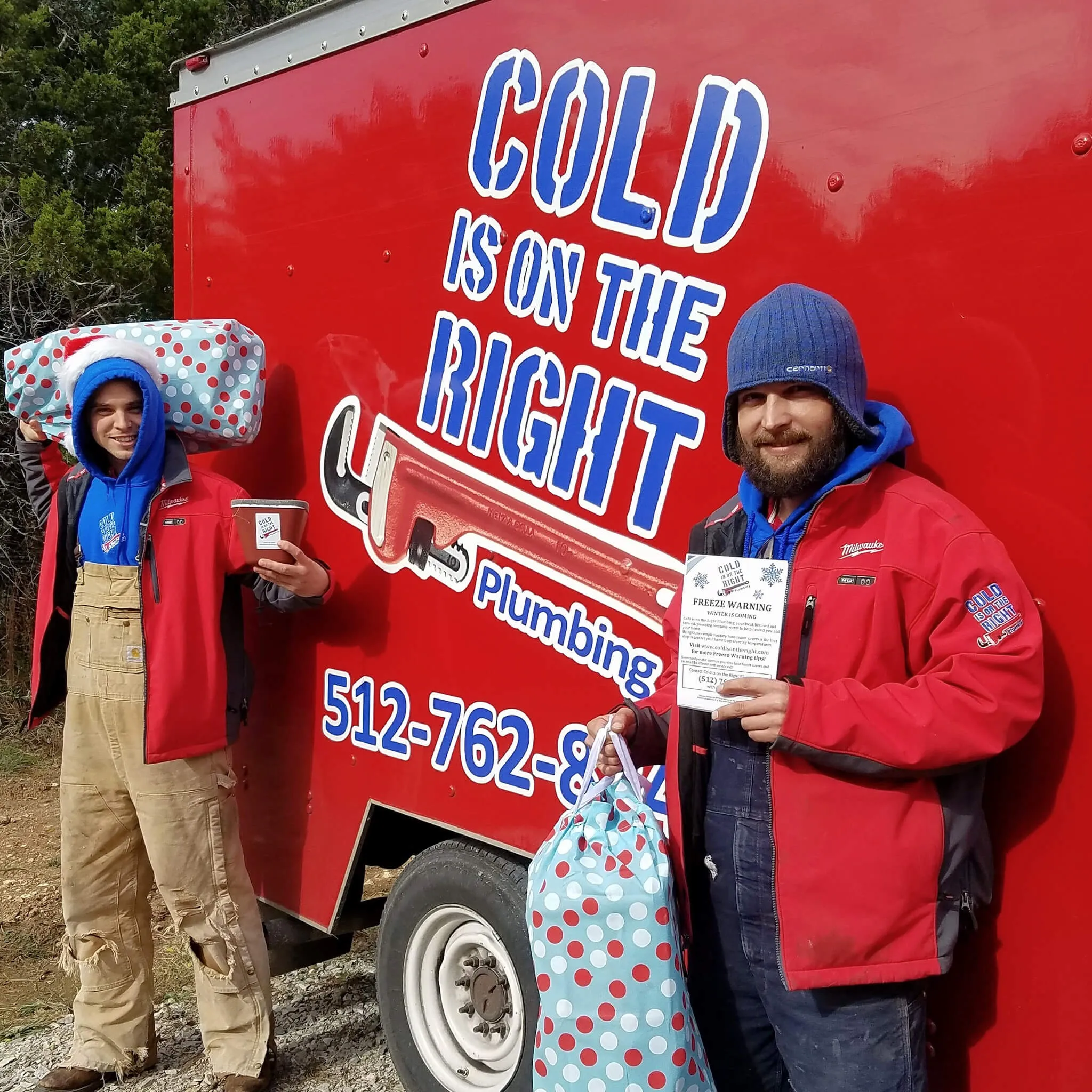 Two plumbers in red jackets holding gifts and a flyer in front of a "Cold is on the Right Plumbing" truck.